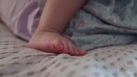 Close up of a baby foot resting on a soft textured blanket in a cozy bedroom Stock Footage 345643193