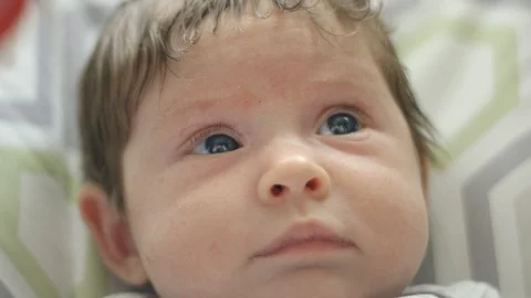 Close-up of baby looking above camera towards toy Stock Footage 107614176