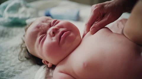 Close up of baby looking upward while caregiver gently massages infant neck 스톡 동영상 331059142