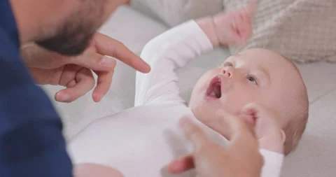 Close up of the baby lying on its back on the couch and looking at its father Stock Footage 140173834