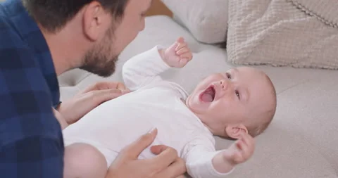 Close up of the baby lying on its back on the couch, smiling and happy, looking Stockbeeldmateriaal 140173961