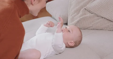 Close up of the baby lying on its back on the couch, smiling and happy, shaking 動画素材 140175567