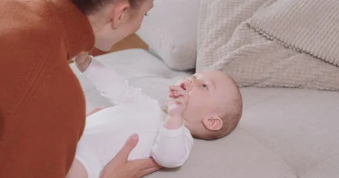 Close up of the baby lying on its back on the couch, smiling and happy, shaking Stock Footage 140176226