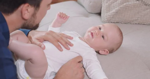 Close up of the baby lying on its back on the couch, smiling and happy, shaking 스톡 동영상 140176848