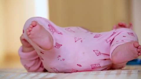 Close up of a baby lying on a soft play mat while gently moving their feet and Stock-Footage 331004928