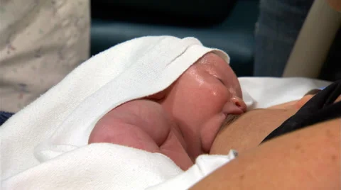 Close-up of baby at mother's breast; nurse checks infant's heart and lungs Stock Footage 59244516
