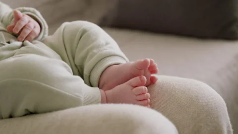 Close-up of a baby's bare feet lying in his mother's arms. Active child playing Stock Footage 304696338