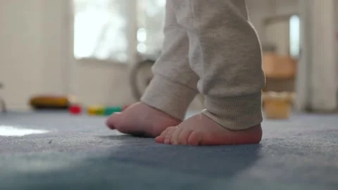 Close-up of a baby's bare feet trying to walk on a soft carpet Stock Footage 341628886