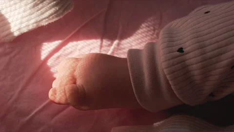 Close up of a baby's bare foot resting on a soft pink blanket, lit by warm 스톡 동영상 322633633