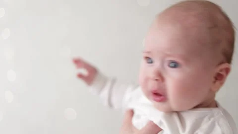 Close-up of a baby's face with expressive eyes and mouth, held by parent Stock Footage 340586947