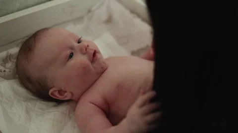 Close-up of a baby's face as a parent's hand gently touches their chest, Stock Footage 340630197