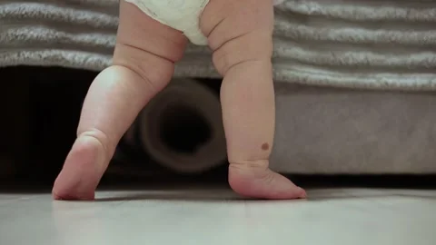 Close-up of baby's feet taking first steps on a wooden floor Stockbeeldmateriaal 342504547