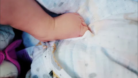 Close up of baby's foot resting on a patterned blanket with natural light 스톡 동영상 316700878