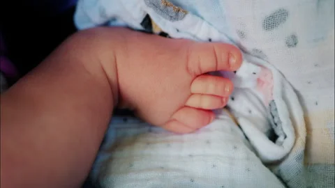 Close up of baby's foot resting on a patterned blanket with natural light 스톡 동영상 316701003