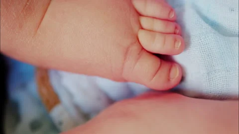 Close up of baby's foot resting on a patterned blanket with natural light 스톡 동영상 316761107