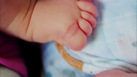 Close up of baby's foot resting on a patterned blanket with natural light 스톡 동영상 316761187