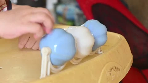 Close up of a baby's hand spinning a ringing ball on the table Stock Footage 256161928