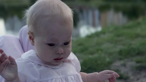 Close-up of a baby's head and shoulders in a light pink dress outdoors Vidéo 342503889