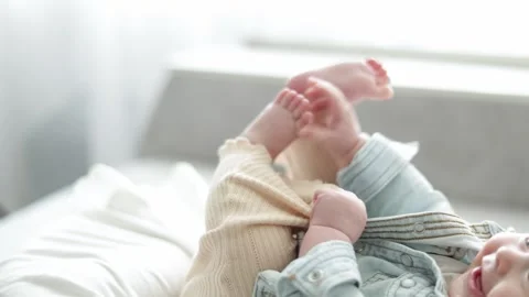 Close-up of a baby's legs and hands playing with clothes on a bright day Stock Footage 340581009
