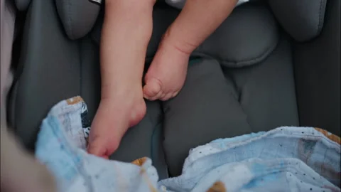 Close up of a baby's small feet moving near a patterned blanket inside a car 스톡 동영상 316633695