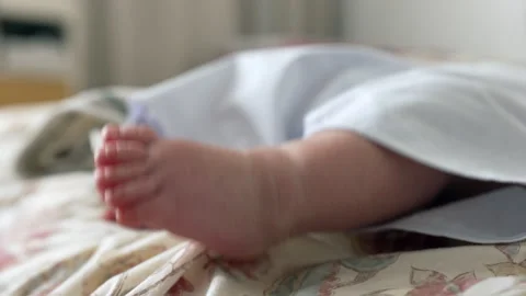 Close-up of a babys tiny foot resting on a patterned bedspread.  the delica.. 스톡 동영상 285851469