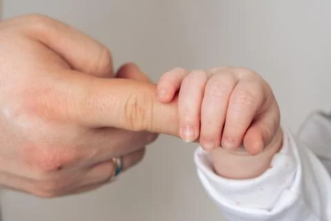 Close-up of a babys tiny hand gently gripping an adult finger, symbolizing trust Foto stock