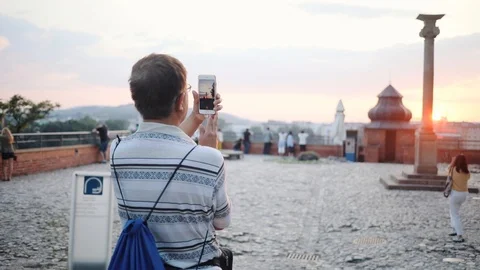 Close up from the back of old man taking photo of sunset in old city caucasian Stock Footage 95448061
