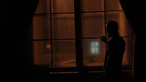 The close-up back portrait of the man standing, looking through the window and Video stock 74114907