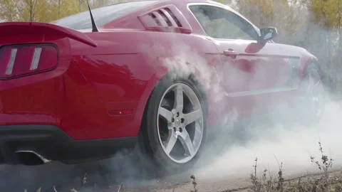 Close-up of the back of a red car, smoke coming from under the rear wheel. Stock Footage 131840531