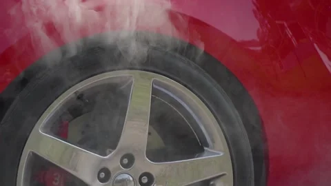 Close-up of the back of a red car, smoke coming from under the rear wheel. Stock Footage 131840536