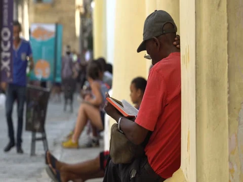 Close-up back view Afro-American man dressed red t-shirt, hat sits on central Stock Footage 69558874