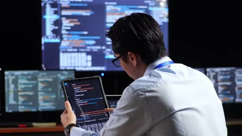Close Up Back View Of Asian Male Programmer Looking At Database On Tablet While Stock Footage 230175320