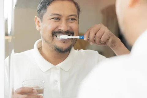 Close-up back view of bearded man holding glass of water with toothbrush cl.. Stock Photos