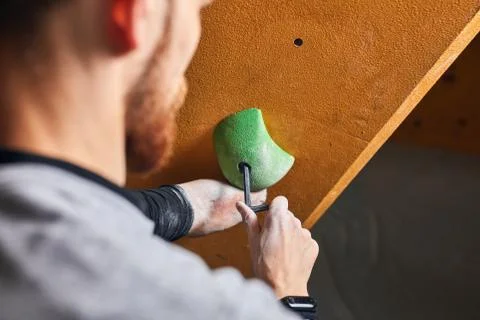 Close up back view of boulderer with physical disability screwing holds at rock Stock Photos