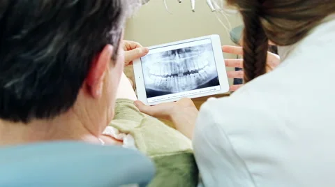 Close up back view of dentist showing X-ray of teeth on tablet to patient Stock Footage 68984954