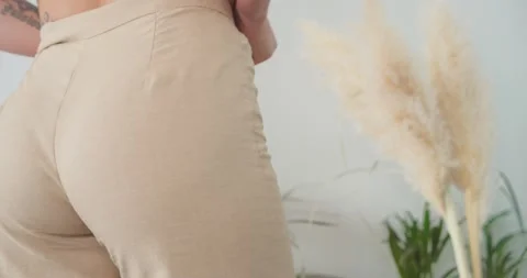 Close up back view of female buttocks wearing beige pants, leaving room. Vidéo 169977917