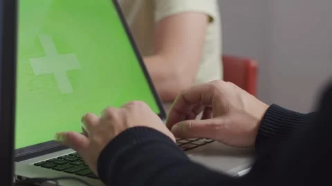Close-up back view a guy is working at a laptop green screen mockup, typing Stock Footage 242448980