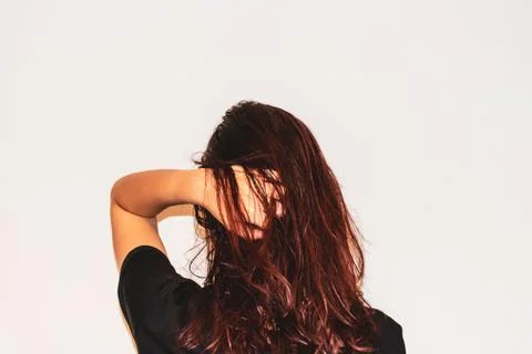 A close-up back view head shot of a young Caucasian woman running her hand th Stock Photos