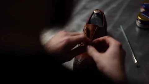 Close-up back view of male shoemaker tying laces on repaired and polished light Video stock 150010681