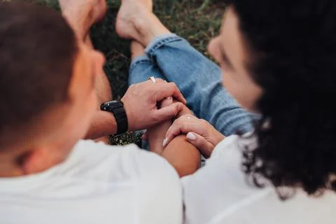 Close Up Back View of Man and Woman Holding by Hands Sitting on the Ground Stock Photos