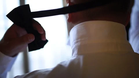 Close up. Back view. A man is dressing a bow tie. The groom dresses a bow tie. Stock Footage 129114590