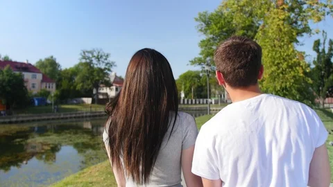 Close up of the back view of nice attractive young couple walking the park. Rear Stock Footage 116627373