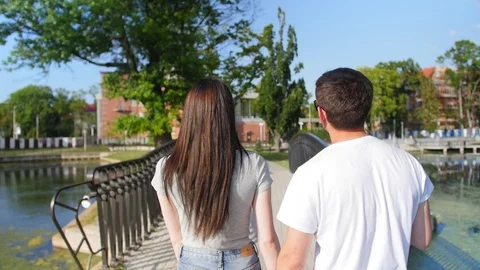 Close up of the back view of nice attractive young couple walking the park. Rear Stock Footage 116628393