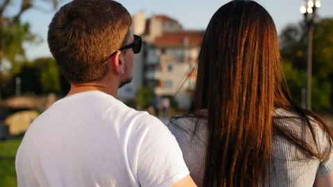 Close up of the back view of nice attractive young couple walking the park. Rear Stock Footage 116702794