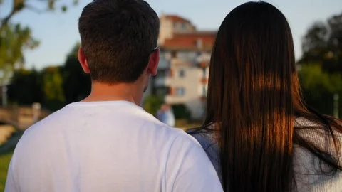 Close up of the back view of nice attractive young couple walking the park. Rear Stock Footage 116703131