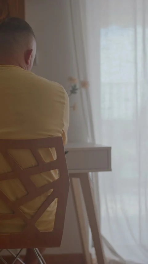A close-up back view of a pensive man sitting at a minimalist desk, gazing out Vídeo Stock 346635876