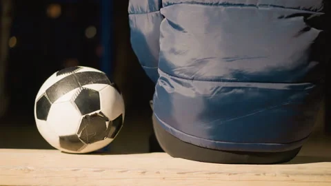 Close Up Back View of Person in Blue Hooded Jacket Sitting with Soccer Ball Stock Footage 283170999