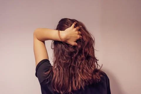 A close-up back view portrait of an unrecognizable young woman with her hand  Stock Photos