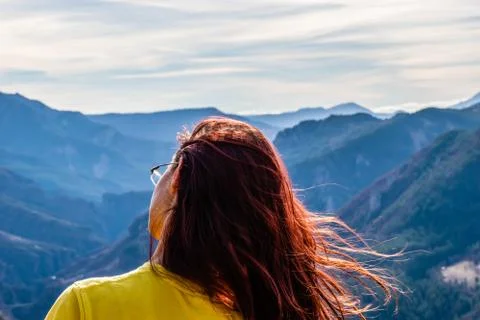 A close-up back view of a young redhead woman wearing glasses with her head t Stock Photos
