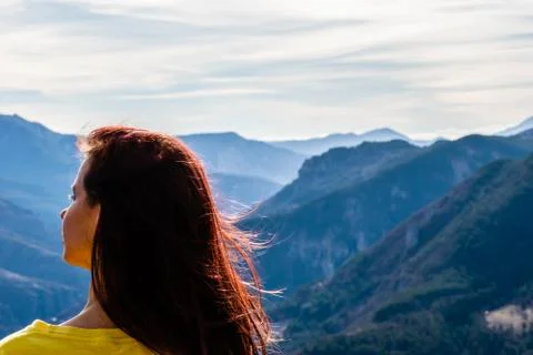 A close-up back view of a young redhead woman with her long hair fluttering i Stock Photos
